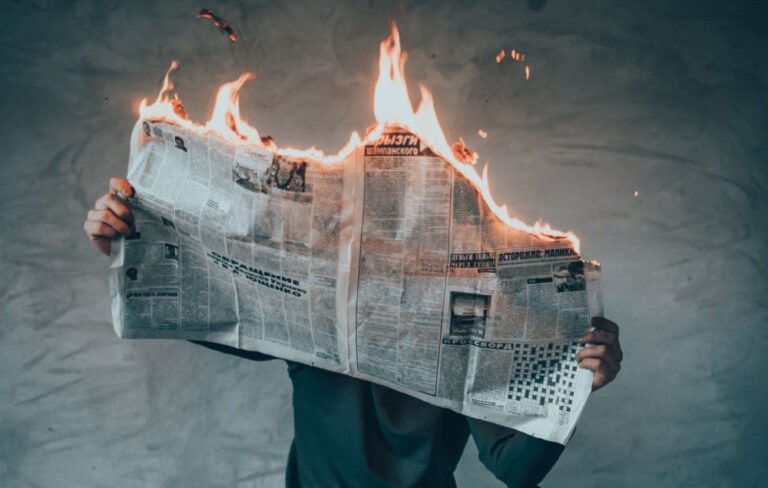 history of happiness. an image of a newspaper burning hold by a person