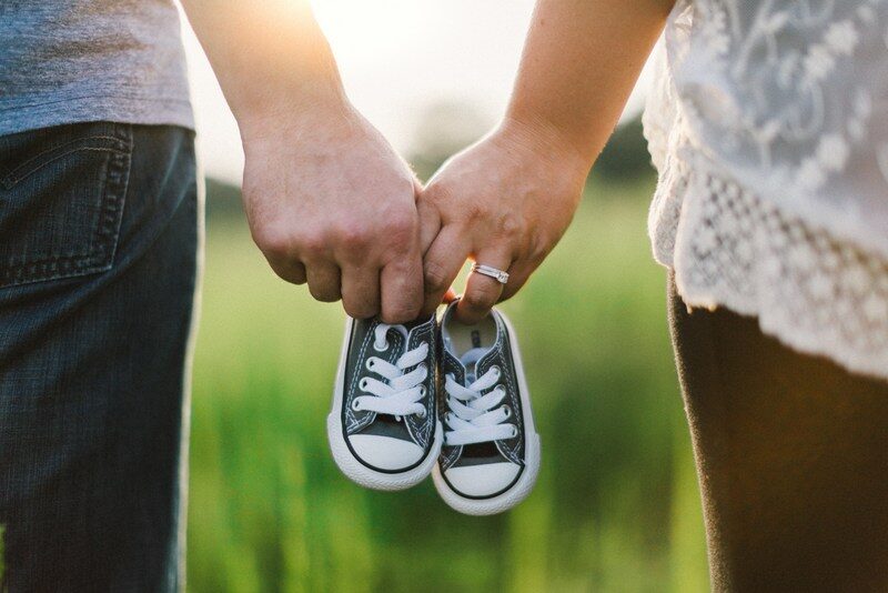 happy relationship, mand hand, and woman hand holding a pair of baby shoes. 