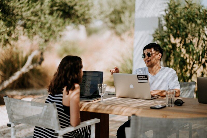 happy relationship, a man and a girl sitting in front of their laptop while talking.