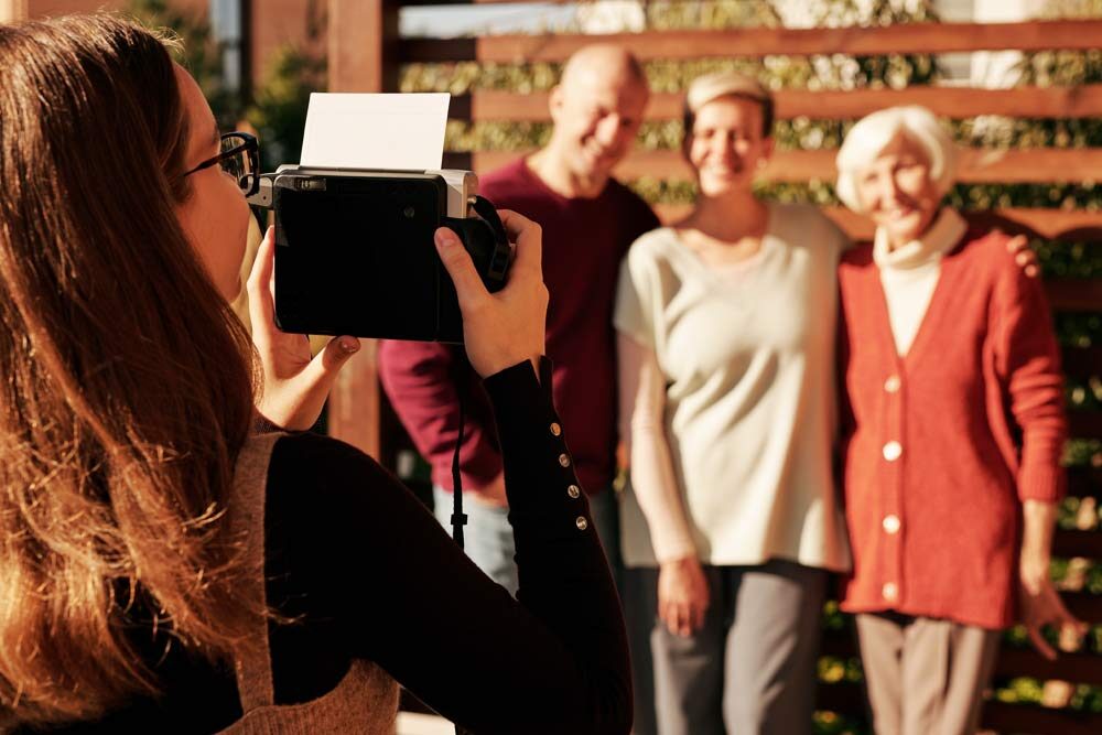 A girl holding a camera and taking a picture of her parents and grandmother