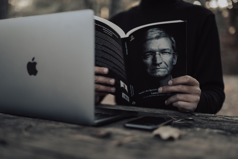Books, Image of a man holding a book with MacBook and phone