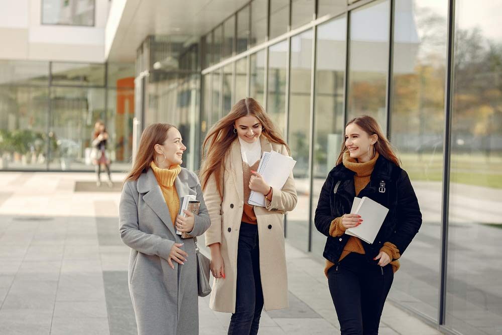 Happiness in schools, an image of three girls talking and smiling while walking
