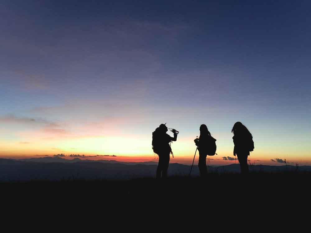 Optimal Happiness, three people hiking on a sunset