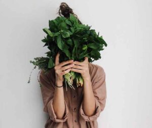Vegetarian diet, a woman holding green vegetables in front of her face
