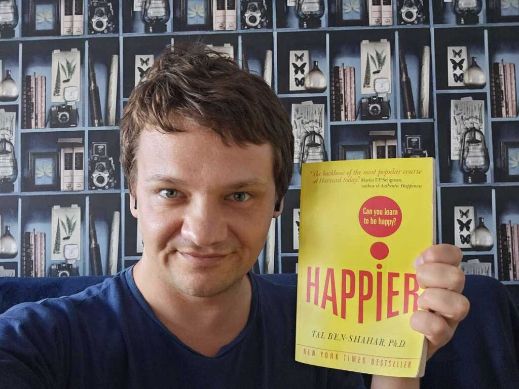 Roman Russo holding ​​Happier by Tal Ben-Shahar: Book Review
